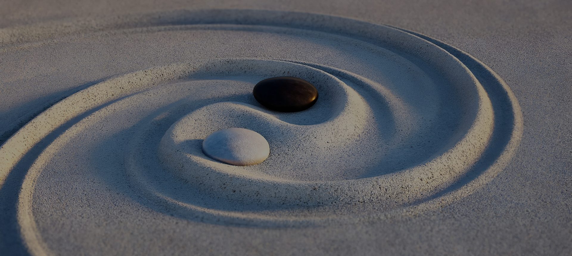 Black and white stones arranged in a Zen sand garden with raked patterns.